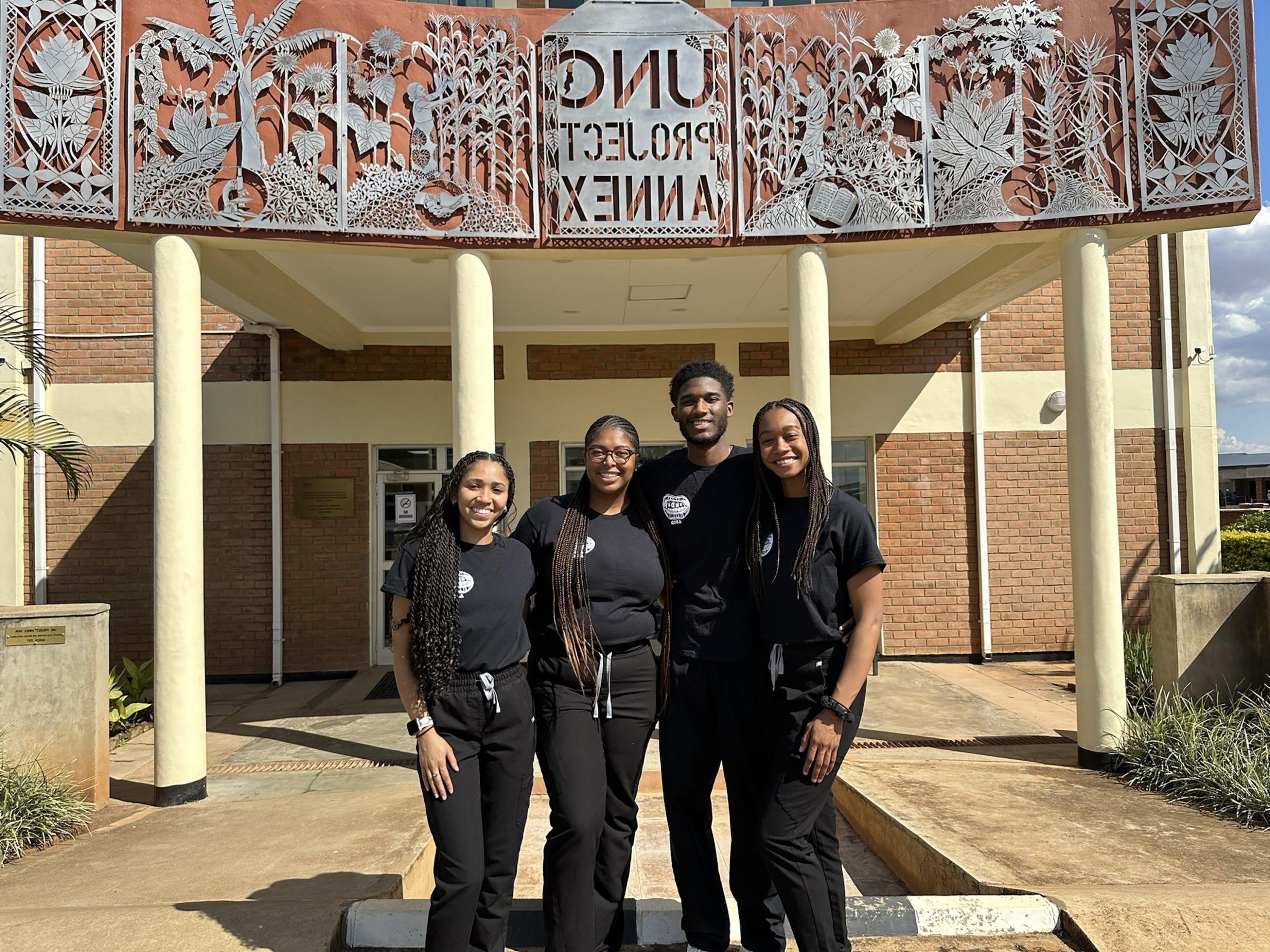 Dentistry students posing in front of building with sign reading "UNC Project Annex".